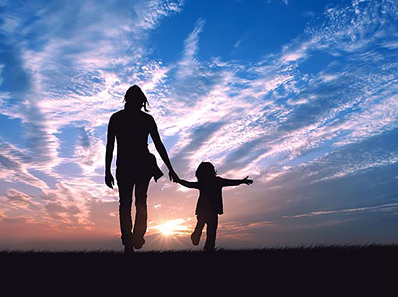 Silhouette of parent and child holding hands in front of sunset